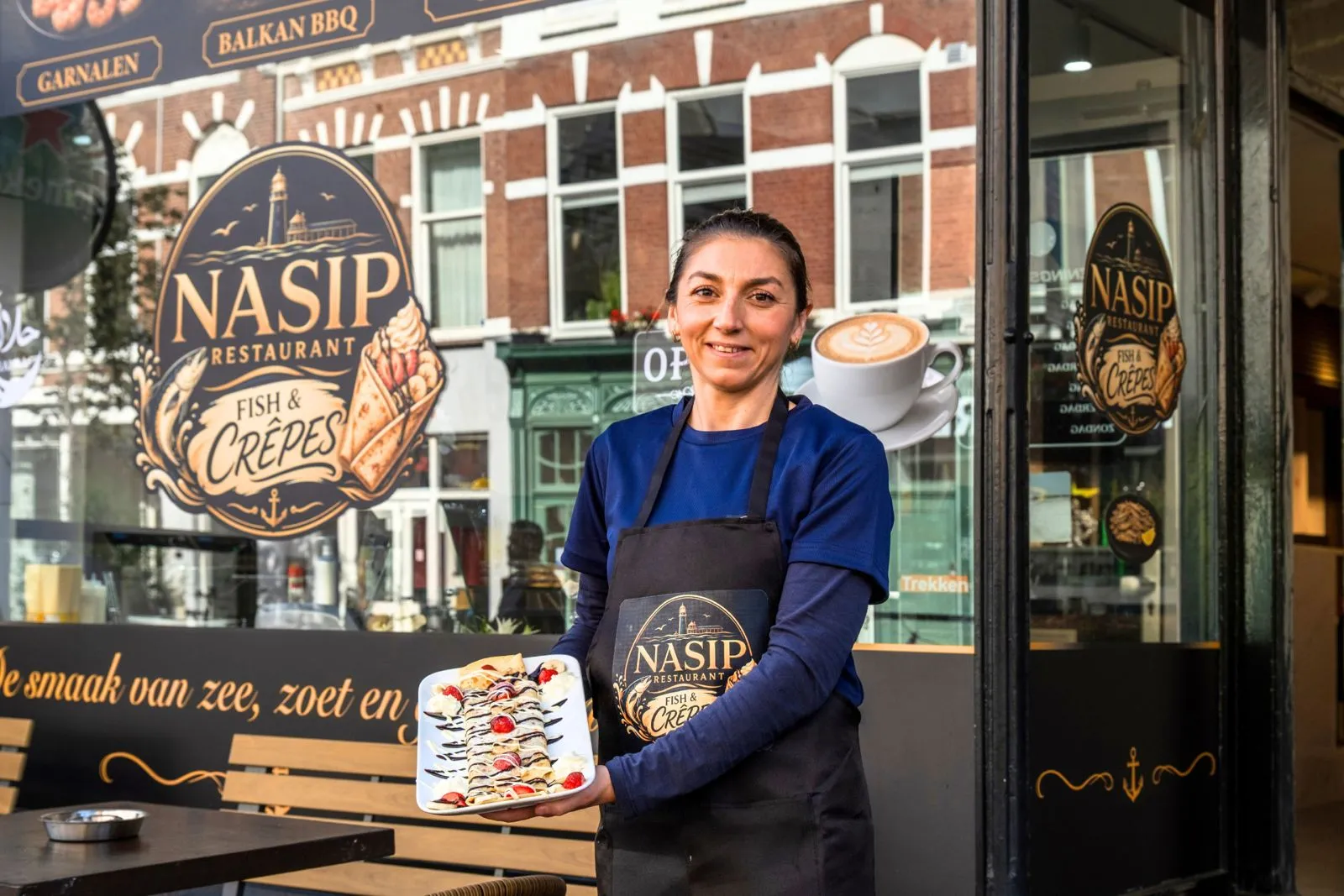 Reni voor de gevel van Nasip aan de Weimarstraat met een crêpe en een cappuccino